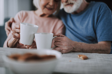 Selective focus white cup in hands of elder couple