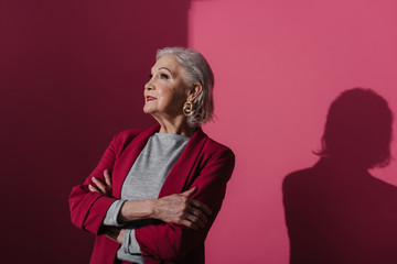 Portrait of charming elderly woman in red jacket isolated on brigth background