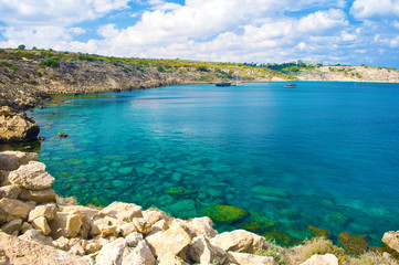 Rock coastline near deep green transparent emerald water
