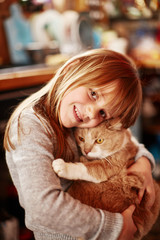 Little girl with a smile keeps a cat