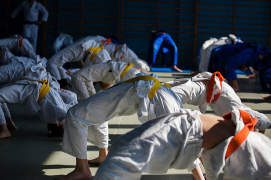 Children do physical exercises during warm-up in judo training