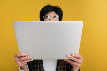 Frightened elderly lady is looking at screen of computer with big eyes