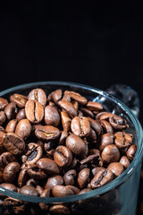 Glass cup of coffee beans on black background