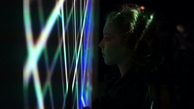 A boy in the dark stands near the big screen, an interactive wall, new technologies in modern education