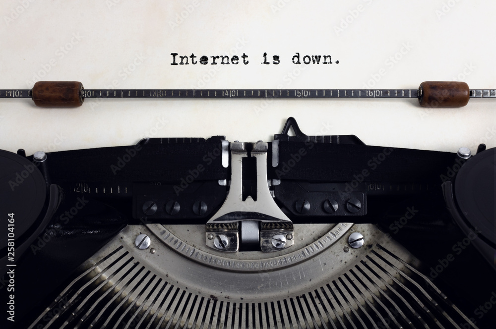 Fototapete old retro vintage black typewriter with close-up typing text internet is down as heading on aged pap