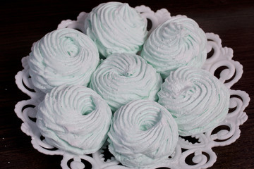 Homemade marshmallows laid on a plate. Marshmallow with mint, with a green tint. On a dark background.