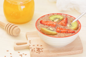 Raw food, vegan breakfast. Raw flaxseed porridge with honey, strawberries and kiwi.
