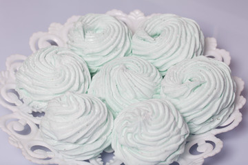 Homemade marshmallows laid on a plate. Marshmallow with mint, with a green tint. On a white background.