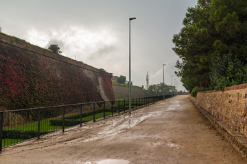 Perspective view of the foopath and walls of the Montjuic Castle in gloomy overcast day, Barcelona, Spain