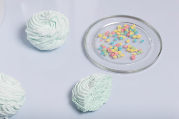 Homemade marshmallows laid on a plate. Marshmallow with mint, with a green tint. Nearby is a piece of marshmallow, its slice is visible. On the white background.