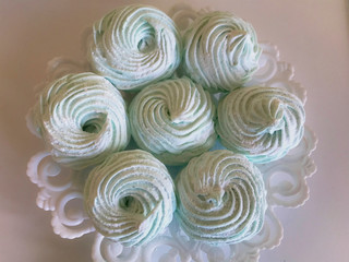 Homemade marshmallows laid on a plate. Marshmallow with mint, with a green tint. On a white background.