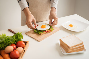 Obraz na płótnie Canvas Hands of man prepare breakfast with sandwich with poached eggs