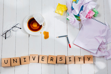 Stationery and word UNIVERSITY made of letters on wooden table background. Education, college, school, stress, student, studying concept. Flat lay or top view