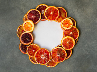 Blood juicy Sicilian orange slices on gray background in circle frame. Sliced blood orange texture....