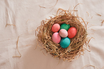 Beautiful Easter multi color egg in straw on wooden background, Easter day concept