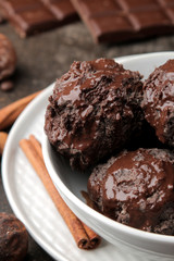 Chocolate ice cream with liquid chocolate with cinnamon stick grains on a dark background. close-up