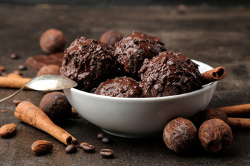 Chocolate ice cream with liquid chocolate with a cinnamon stick and coffee beans on a dark background.