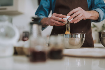 Hands of man cracking and pouring egg into bowl