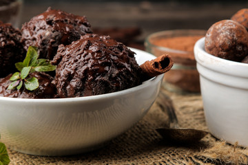 Chocolate ice cream with liquid chocolate with a cinnamon stick on a dark background.
