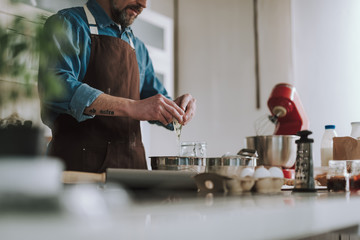 Close up of man pouring egg into the bowl while cooking