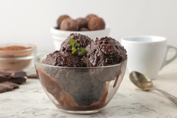 Chocolate ice cream with liquid chocolate on a light concrete background.