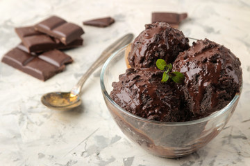 Chocolate ice cream with liquid chocolate on a light concrete background.