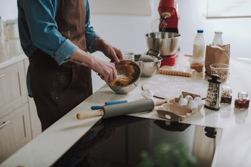 Kitchen table with products and person beating up eggs