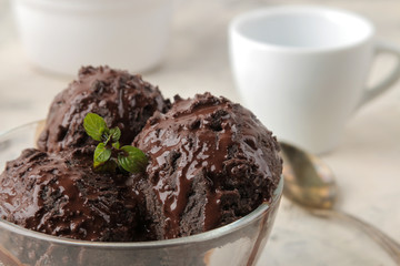 Chocolate ice cream with liquid chocolate on a light concrete background.