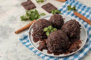 Chocolate ice cream with liquid chocolate on a light concrete background.
