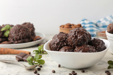 Chocolate ice cream with liquid chocolate and cinnamon sticks on a light concrete background.