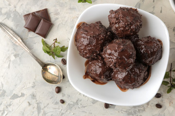 Chocolate ice cream with liquid chocolate on a light concrete background. top view