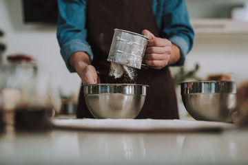 Flour sifting into the bowl from the hand shape sifter