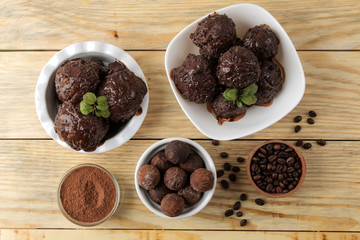 Chocolate ice cream with liquid chocolate and cocoa powder on a natural wooden background. top view