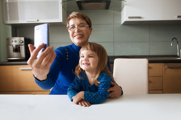 Grandmother and child granddaughter using cellphone together. Senior spending quality time with her...