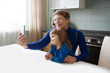 Grandmother and child granddaughter using cellphone together. Senior spending quality time with her grand daughter 