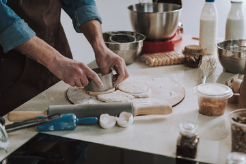 Man using round cookie cutter on the dough