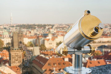 Fototapeta na wymiar Binoculars on the viewpoint. Beautiful aerial view of the traditional old or medieval architecture in Prague in the Czech Republic is blurry ahead.