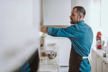 Waist up of the man opening while cupboard