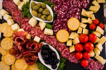 Meat dish with ham, crackers, tomatoes, olives and sausage