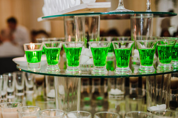 Alcoholic drinks of green color in glass cups