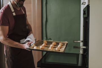 Close up of hot baking pan in hands of smiling man