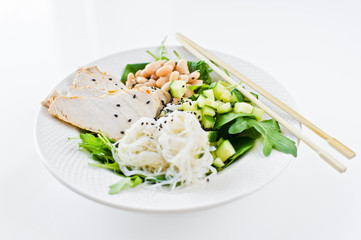 Healthy balanced food, bowl of glass noodles, beans, chicken breast, spinach, arugula and cucumber. White background, side view