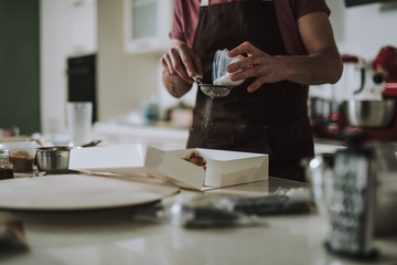 Hands of man sifting powdered sugar through the sieve