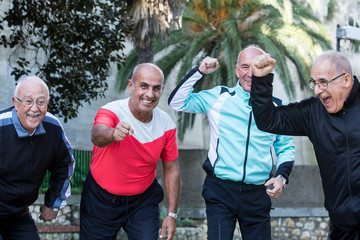 Gruppo di amici anziani festeggia e si diverte al parco in tuta da ginnastica