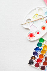 Palette with paintbrush and watercolors, top view, vertical