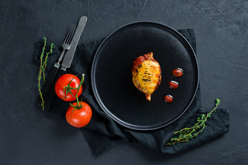 Baked squid in tomato sauce on a black plate. Black background, top view, space for text