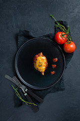 Baked squid in tomato sauce on a black plate. Black background, top view, space for text