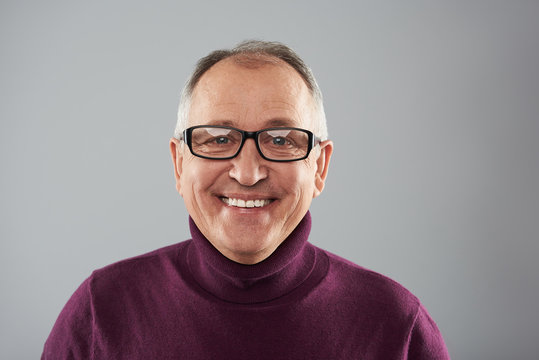 Portrait of smiling man in glasses against the grey background