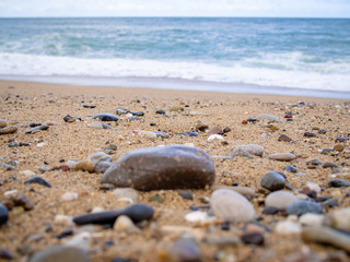 Pebbles on the beach close up on the sea surf background, copy space