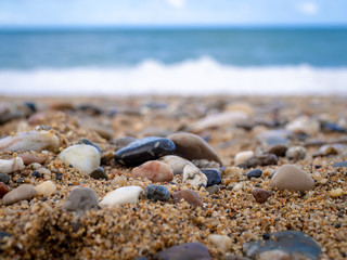 Pebbles on the beach close up on the sea surf background, copy space